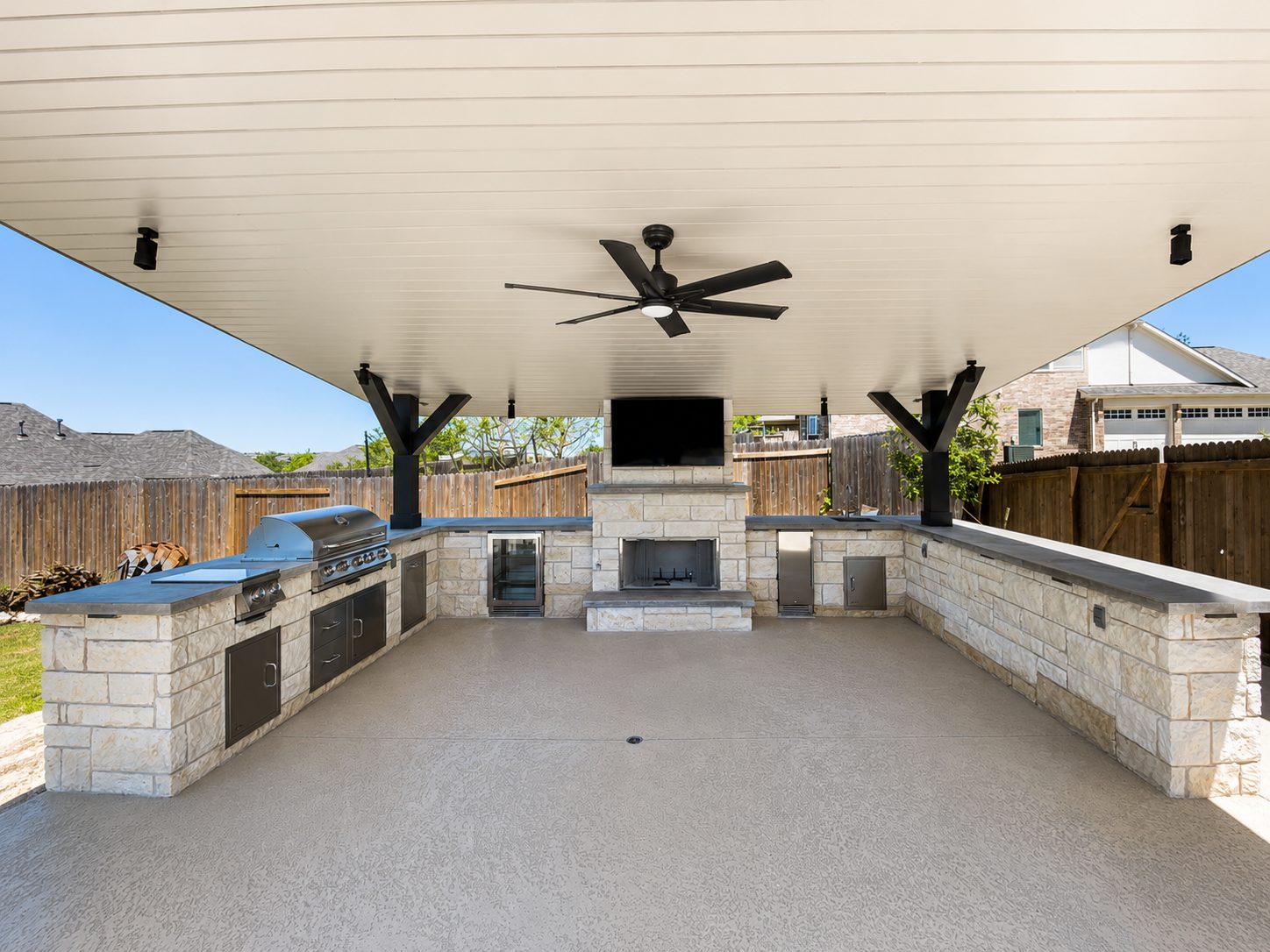 Full covered outdoor pavilion with stacked-stone fireplace and built-in grill — Austin area